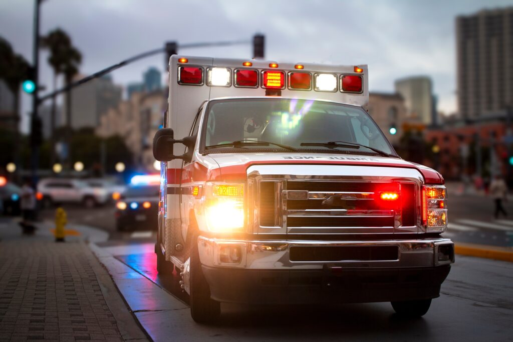 Ambulance with lights on under overcast skies downtown