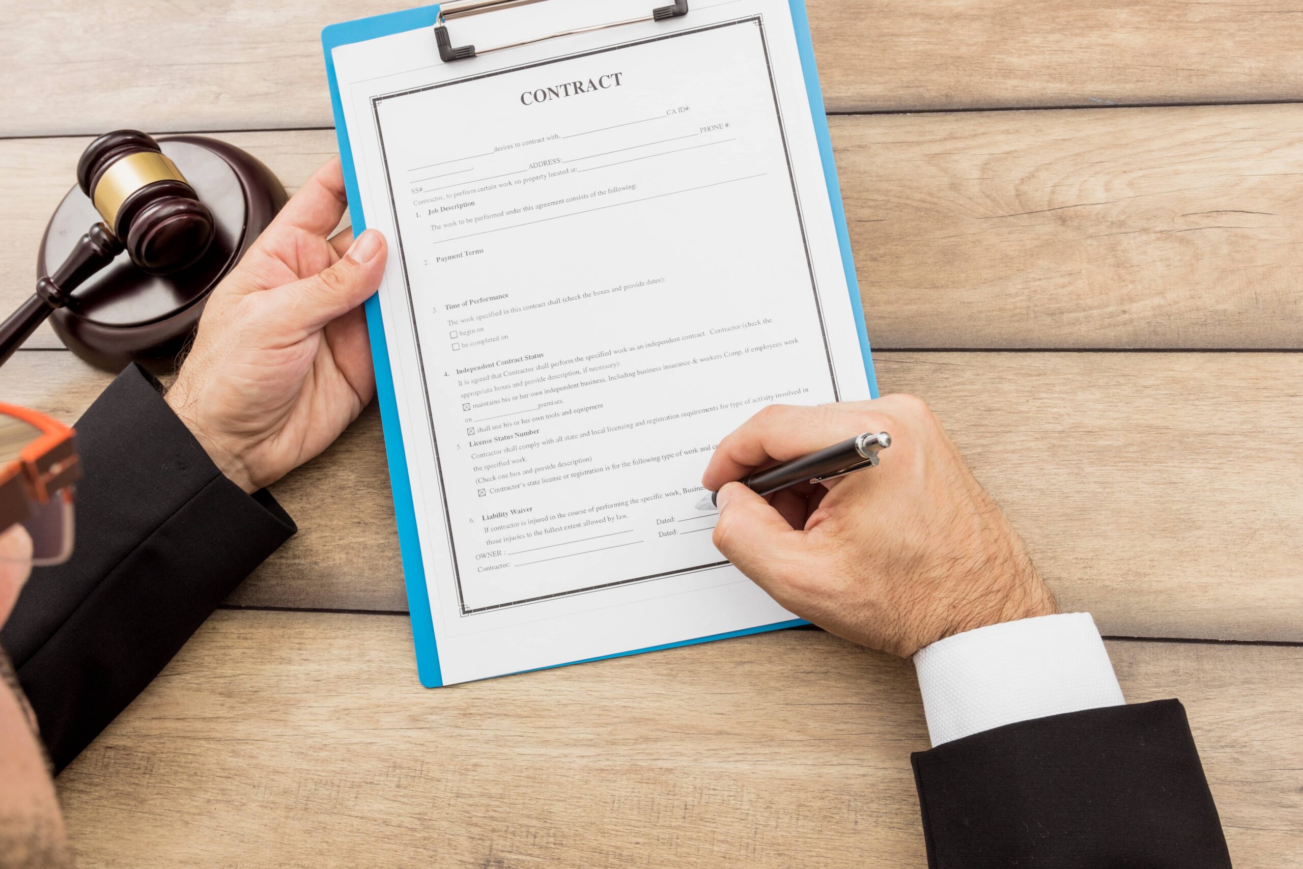 Persona firmando una declaración bajo juramento durante una deposición legal previa al juicio con la orientación de su abogado.