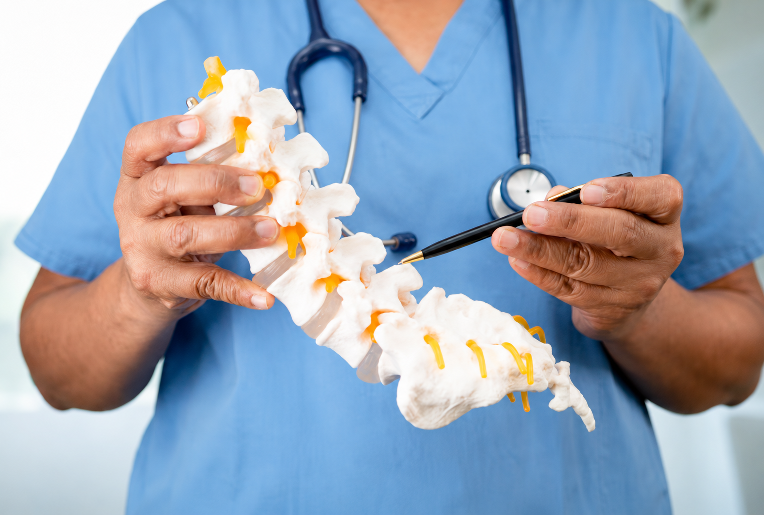 Médico mostrando un modelo de columna vertebral para explicar una lesión medular.